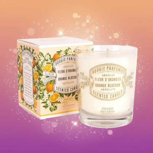 Scented candle with packaging featuring orange blossoms and floral design on a white background