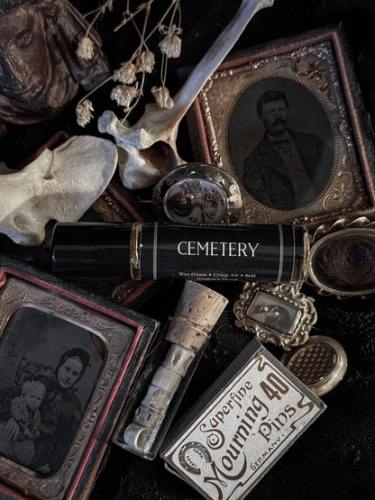 Vintage-style items including a skull, photo album, and 'Cemetery' book on a dark background.