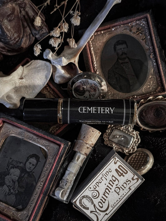 Vintage-style items including a skull, photo album, and 'Cemetery' book on a dark background.