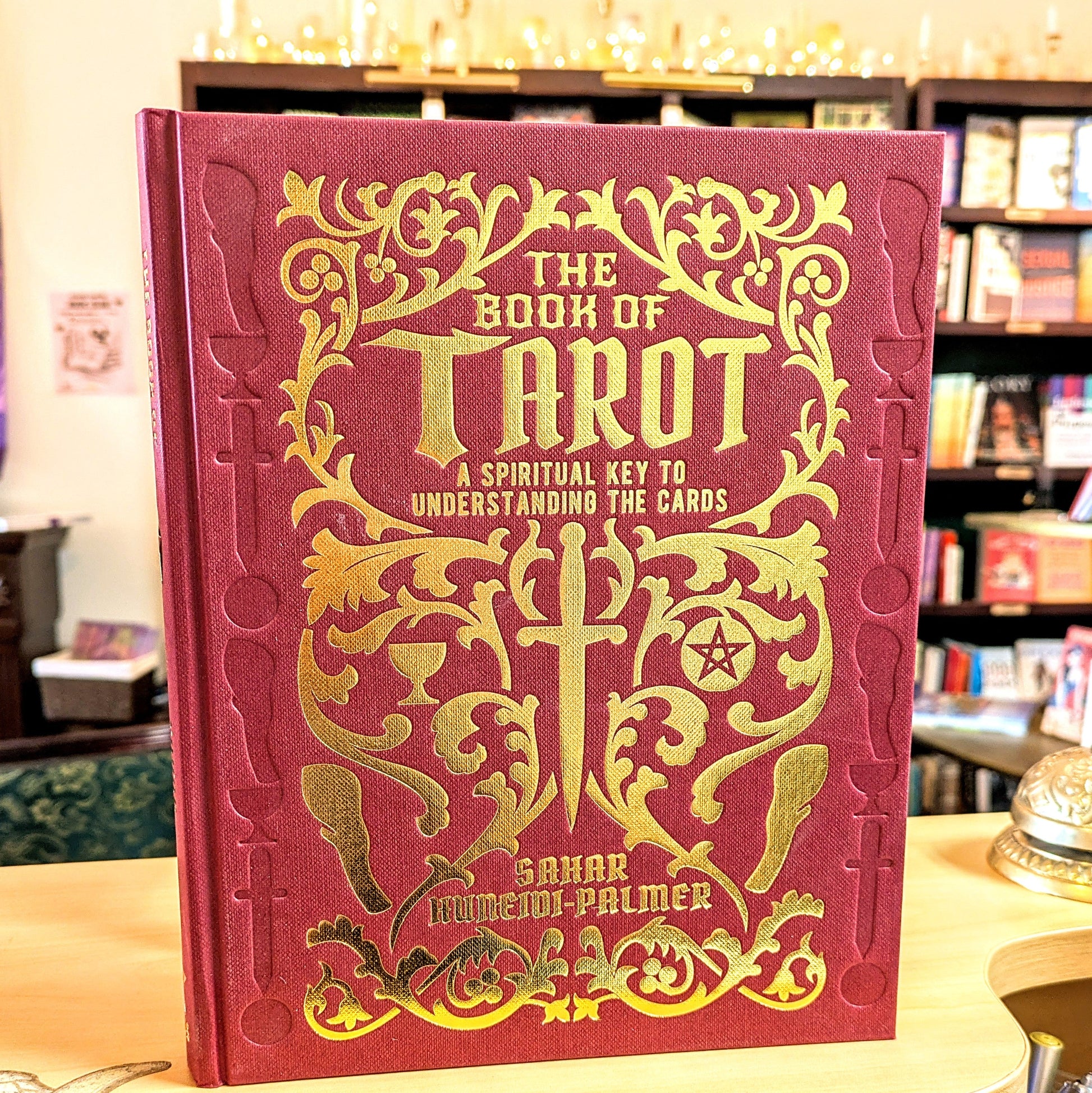 Red book titled 'The Book of Tarot' with gold text and designs on a table.