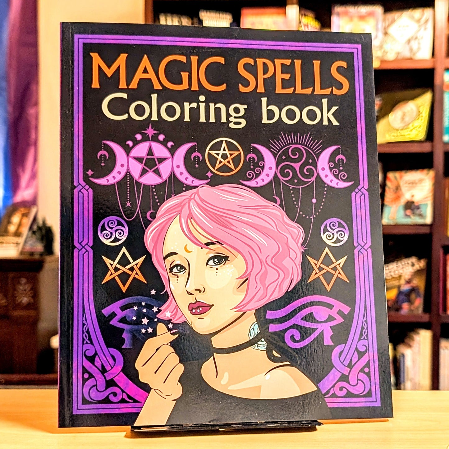Coloring book titled 'Magic Spells' with a cover featuring a woman with pink hair and wiccan symbols.