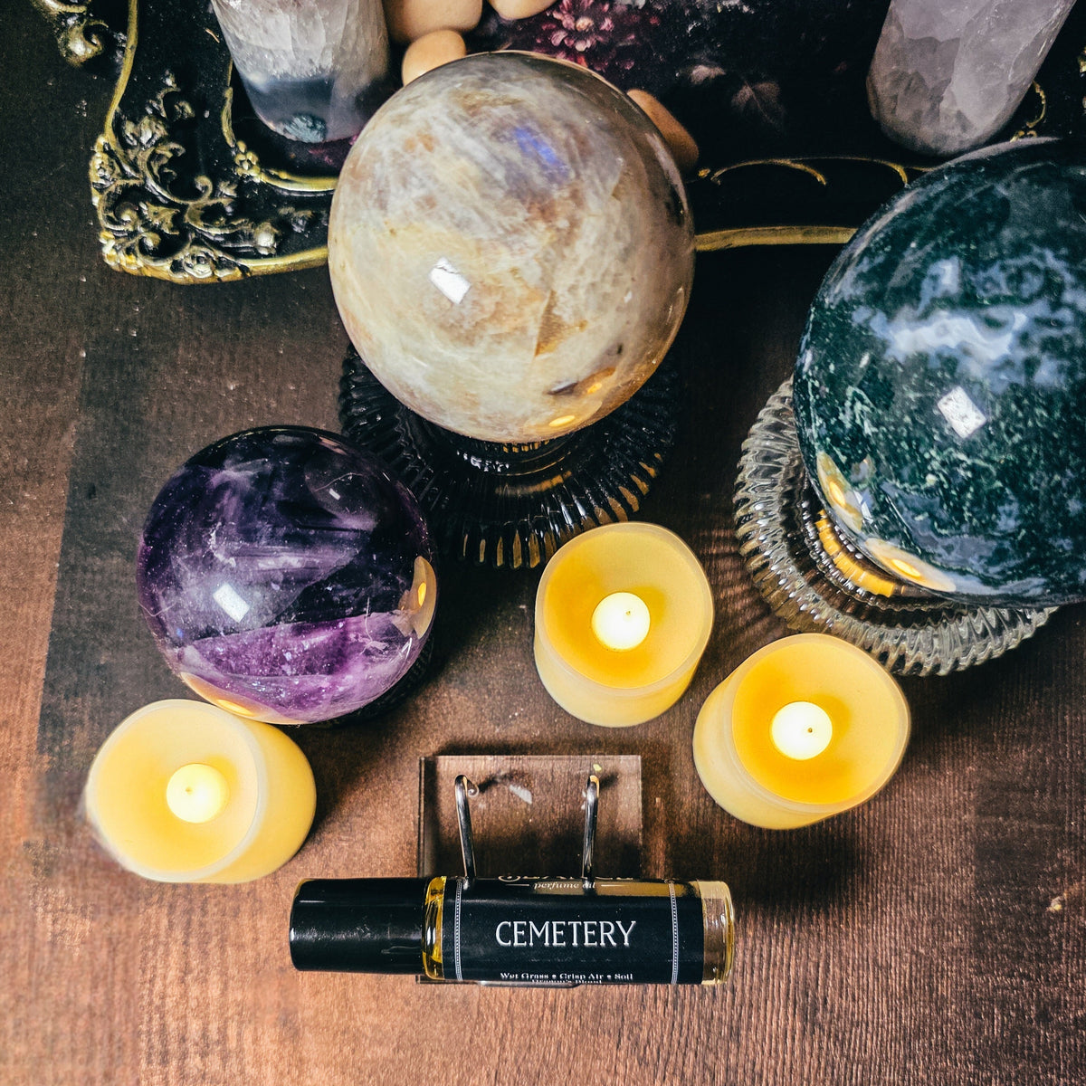 Crystal balls, candles, and a bottle labeled 'Cemetery' on a wooden surface