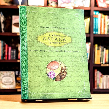 Green book titled 'Ostara' with rabbit and flower illustration on a bookshelf background