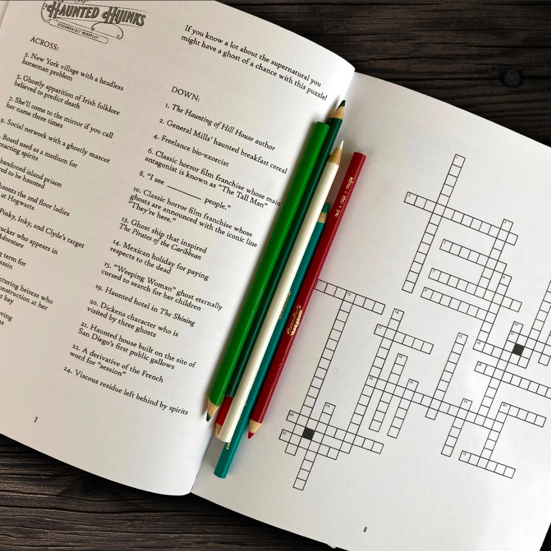 Open book with crossword puzzle and pencils on a wooden surface