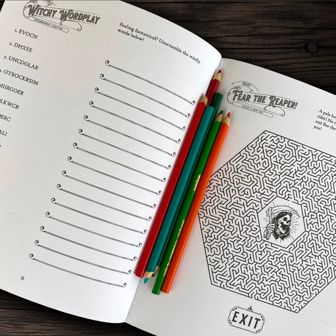An open printed coloring/activity book spread on a dark wood surface, showing a word list page on the left and a maze page on the right, with four colored pencils placed across the center.