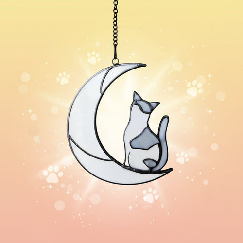 Decorative glass cat on a moon ornament with a chain on a white background