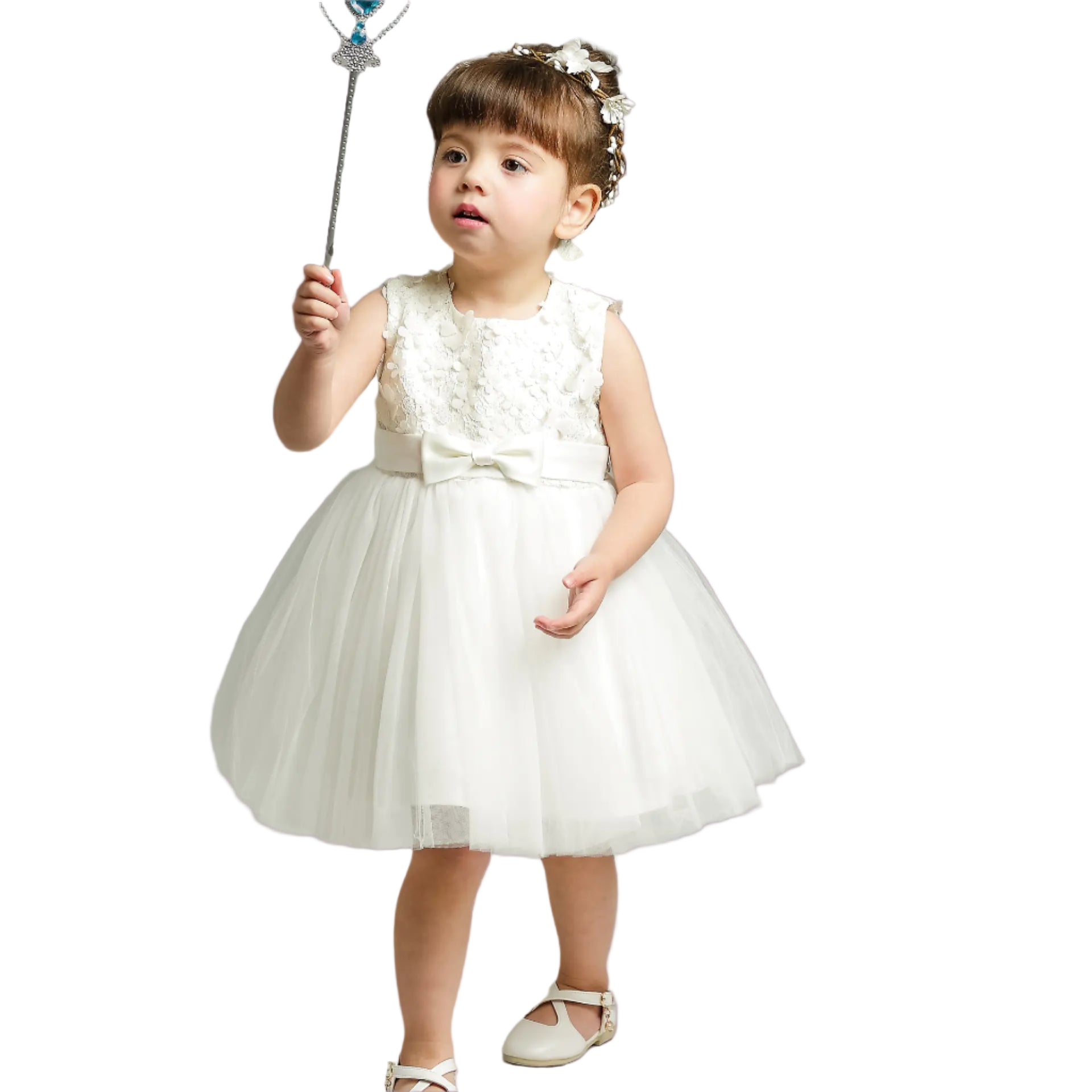 Young girl in a white dress holding a wand against a plain background