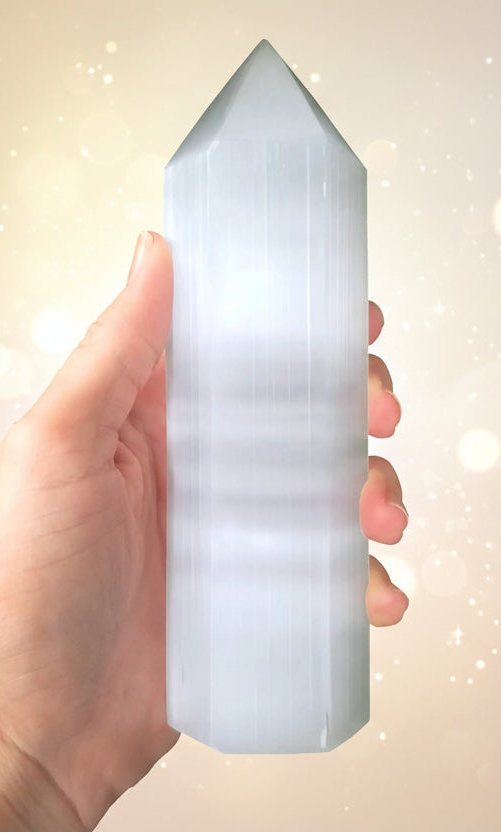 Hand holding a crystal pyramid with a white background