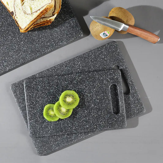 Set of gray speckled cutting boards with sliced kiwis and a knife on a gray surface.