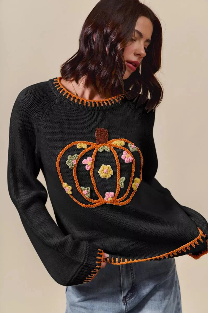 Black sweater with a pumpkin design on a beige background