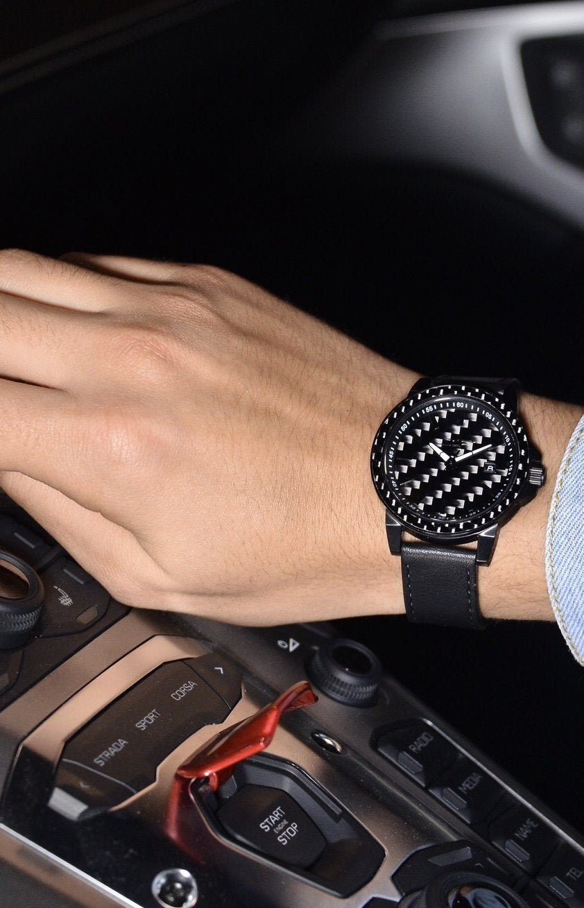 Person wearing a black watch inside a car, with focus on the watch.
