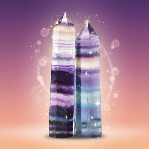 Two multicolored crystal towers on a white surface with a blurred background