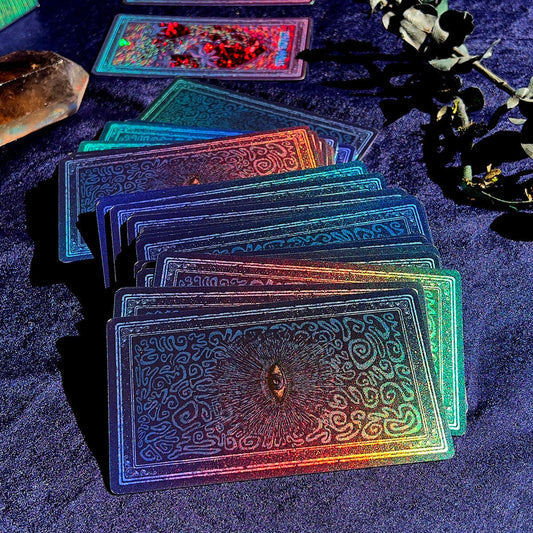 Set of iridescent tarot cards on a dark surface with mystical elements.