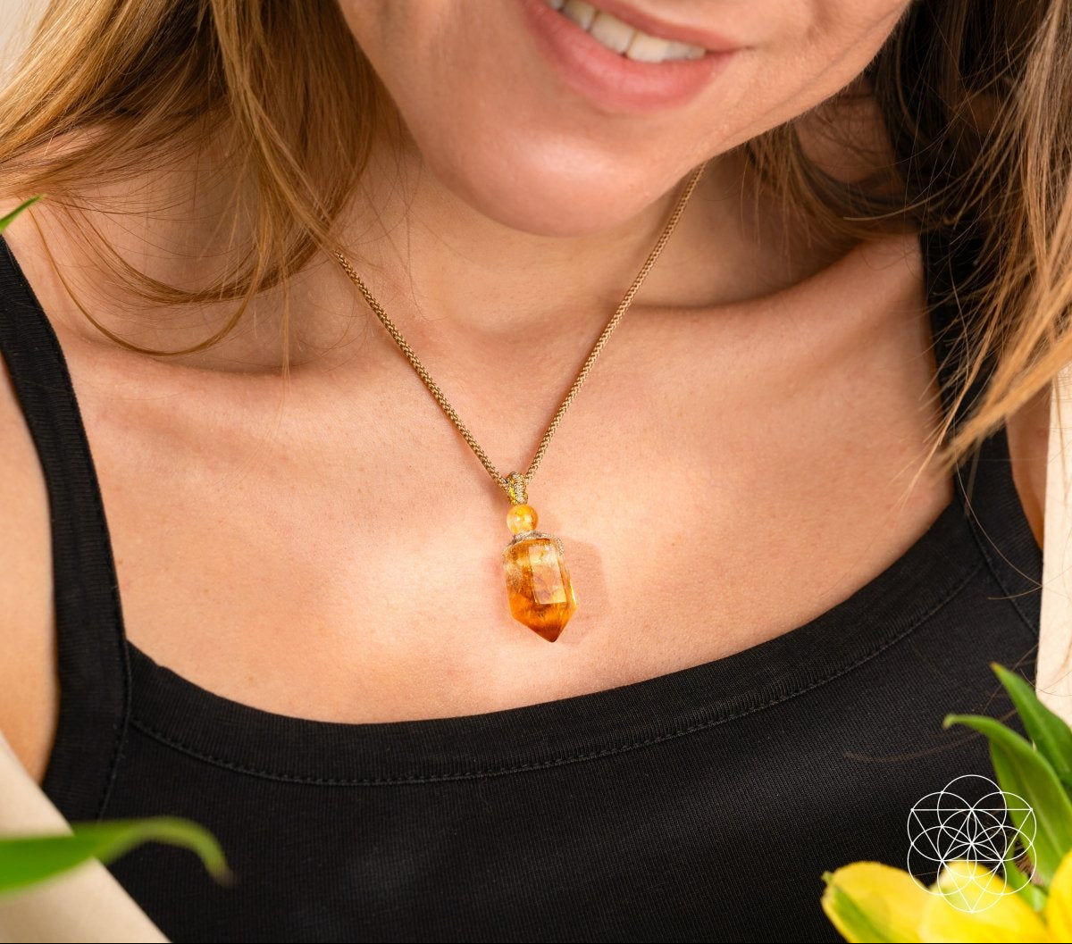 Woman wearing a necklace with a large amber pendant, surrounded by greenery.