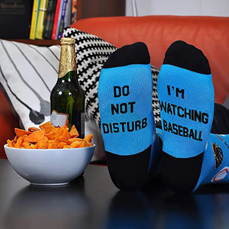 Two socks with humorous text on a table with snacks and a bottle.
