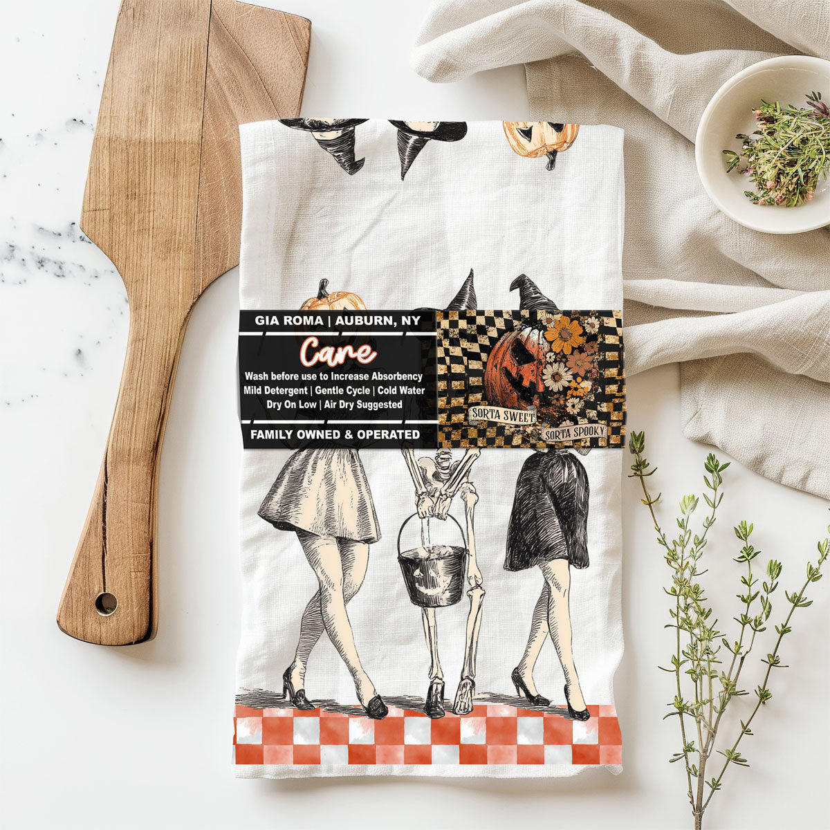 Tea towel with Halloween-themed design on a white surface with kitchen items.