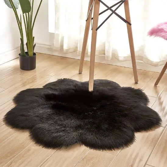 Black fluffy rug on a wooden floor with a plant and chair in the background
