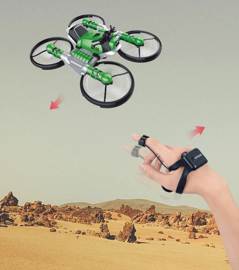 Green drone flying over a desert landscape with a hand wearing a remote control device.