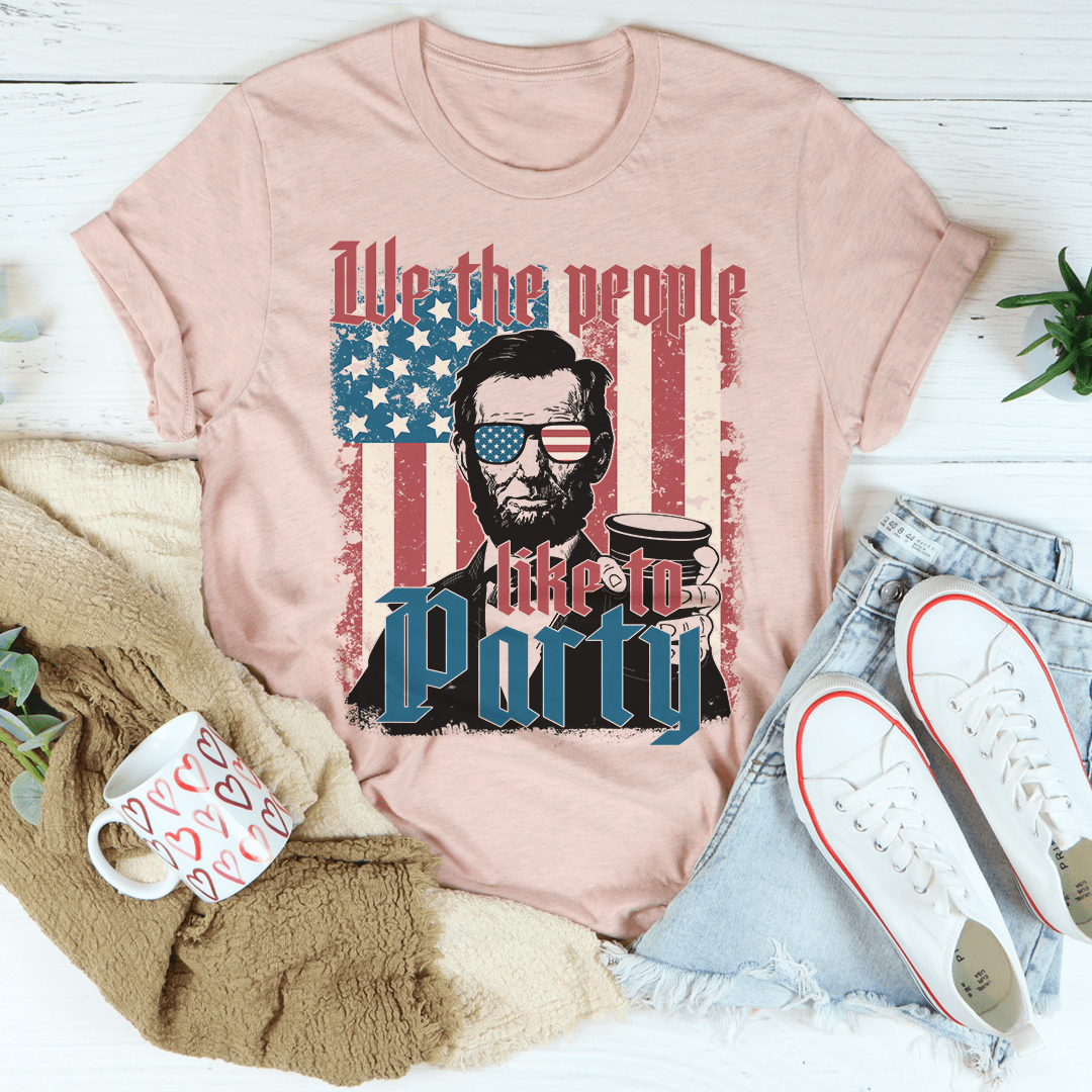Pink t-shirt with graphic design featuring a person holding a coffee cup and American flag, surrounded by casual items.
