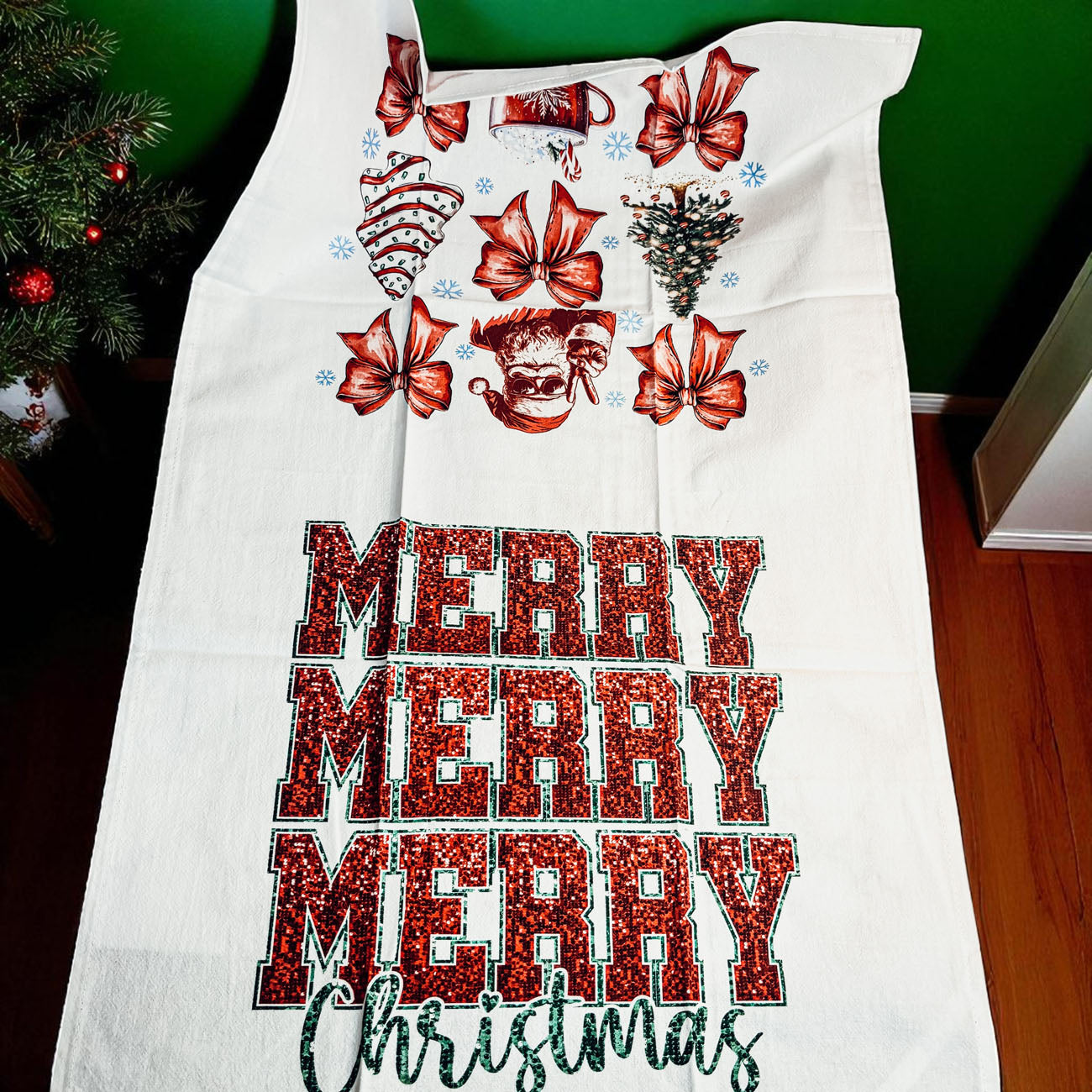 White apron with red Christmas-themed designs and 'Merry Christmas' text on a green background.