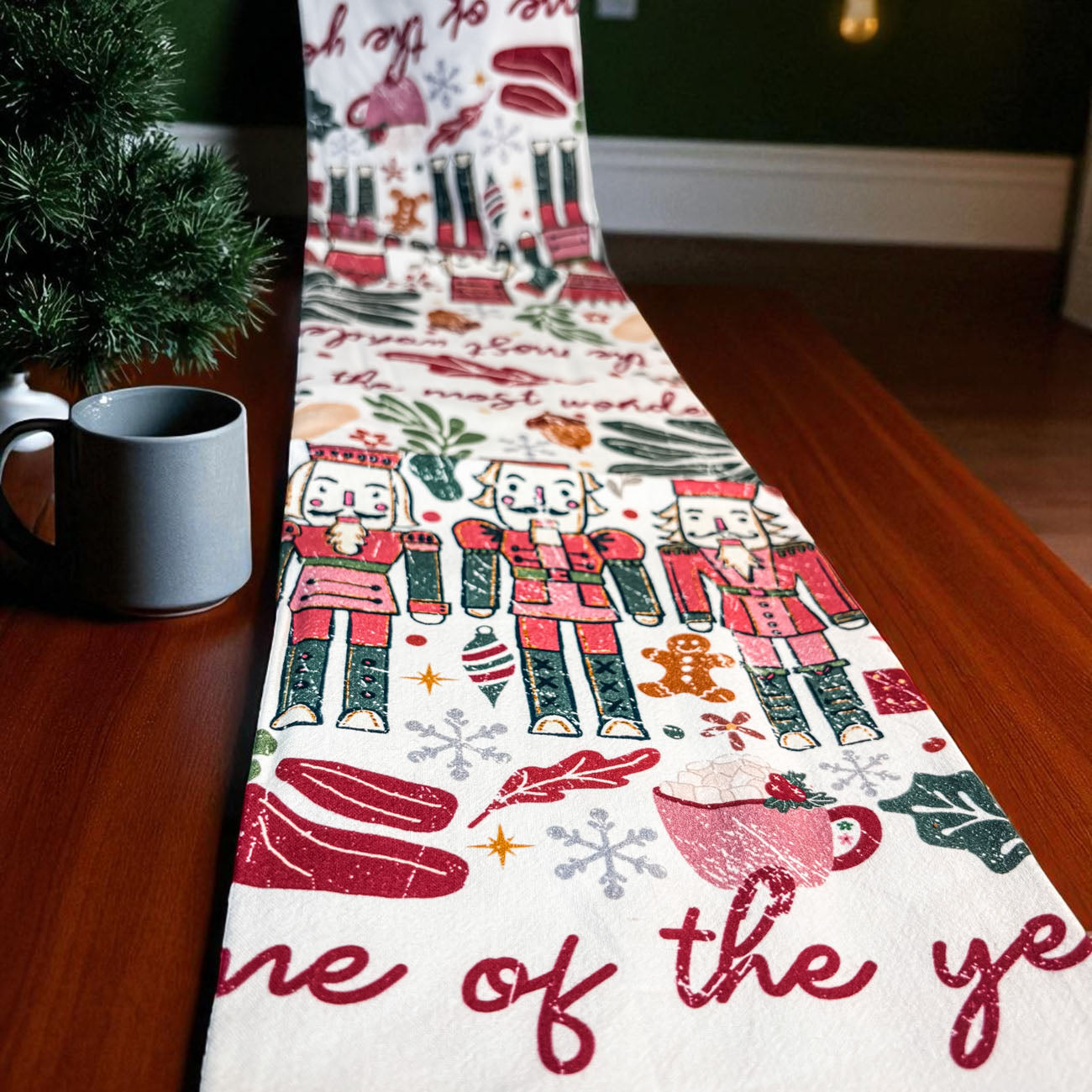 Christmas-themed table runner with nutcrackers and text on a wooden table.