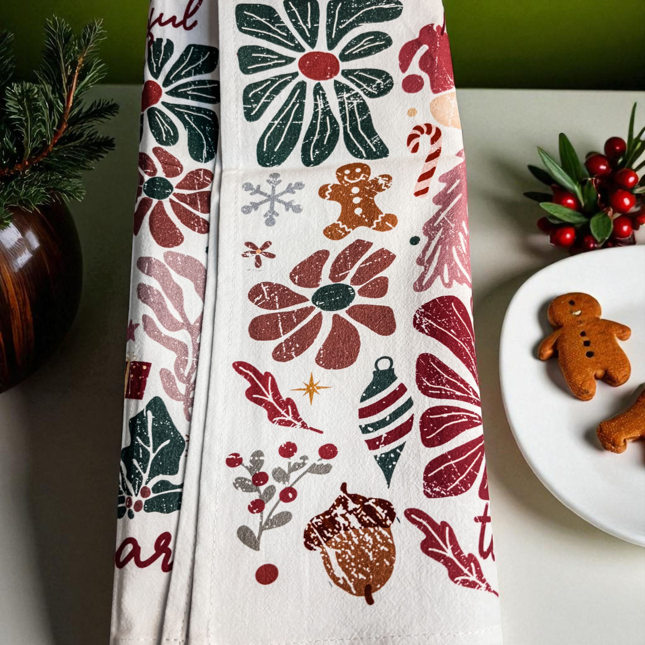 Decorative towel with Christmas patterns on a table with cookies and greenery