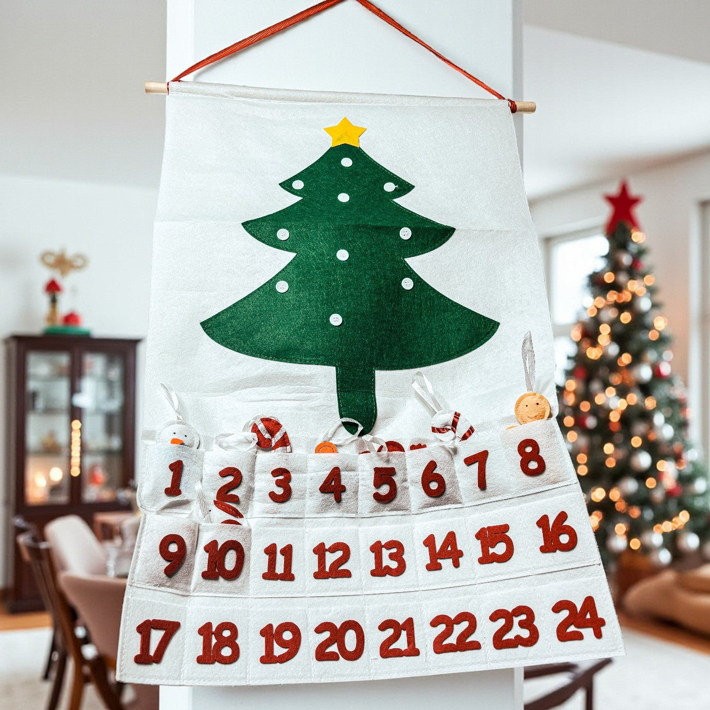 Felt Christmas tree advent calendar with numbered pockets in a festive room.