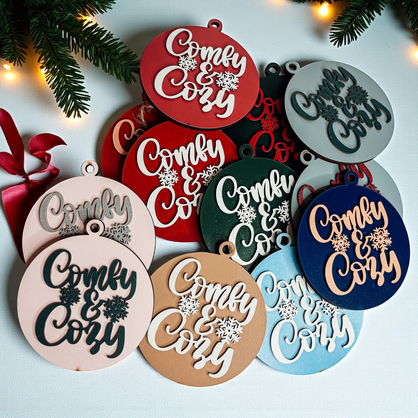 Decorative ornaments with 'Comfy & Cozy' text on a light background with Christmas decorations.
