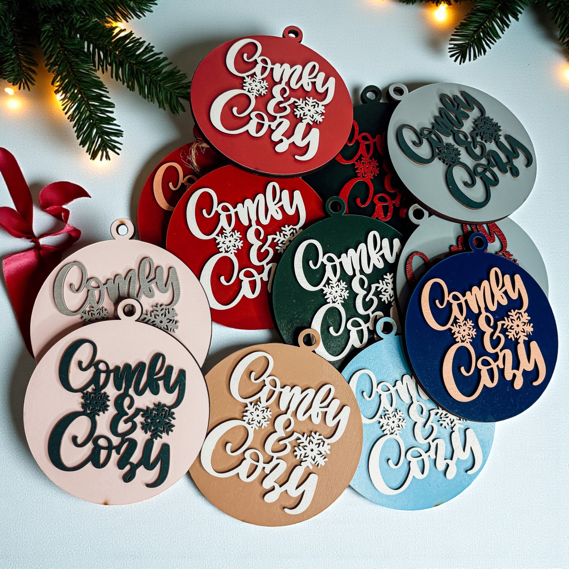 Decorative ornaments with 'Comfy & Cozy' text on a light background with Christmas decorations.