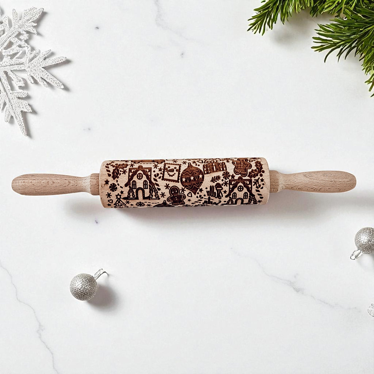 Wooden rolling pin with Christmas patterns on a white surface with holiday decorations.