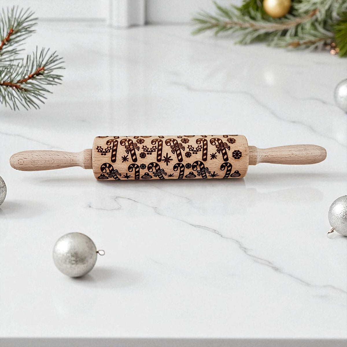 Wooden rolling pin with Christmas patterns on a marble surface with festive decorations.