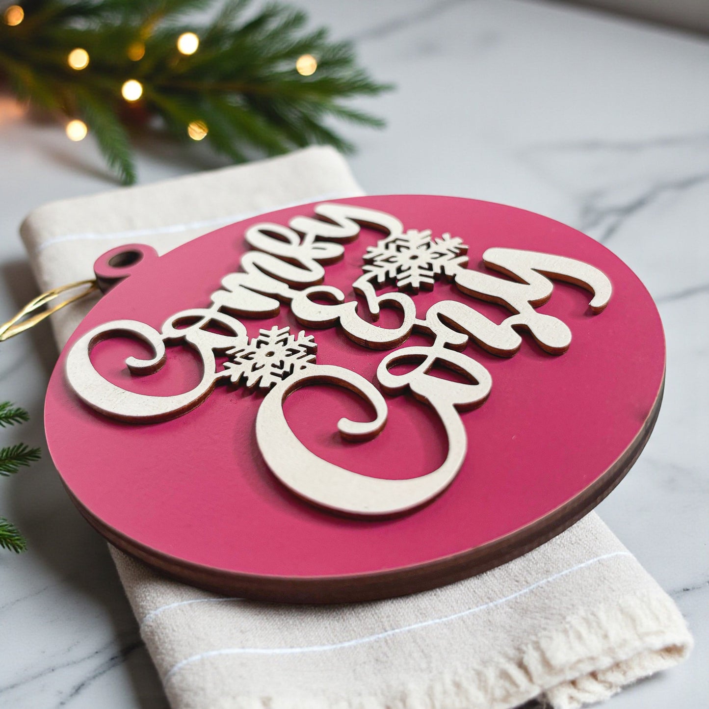 Decorative Christmas ornament with 'Merry Christmas' text on a pink background