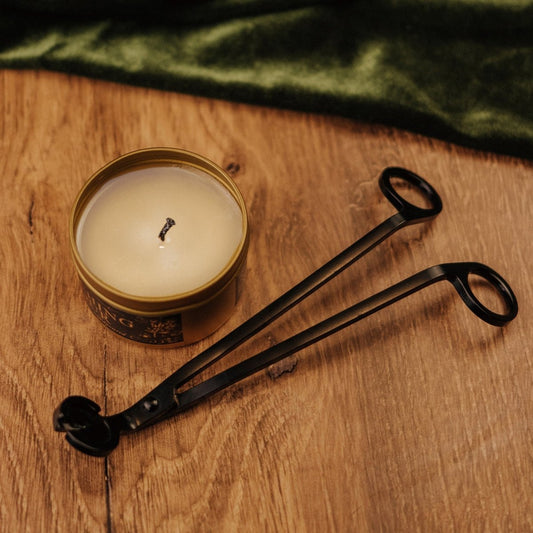 Candle in a tin with tongs on a wooden surface