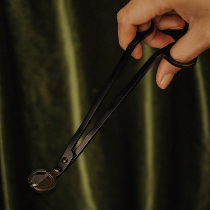 Hand holding a pair of black pliers against a dark background