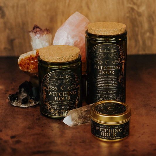Three 'Witching Hour' candles from Phaeton Rose on a wooden surface with crystals.