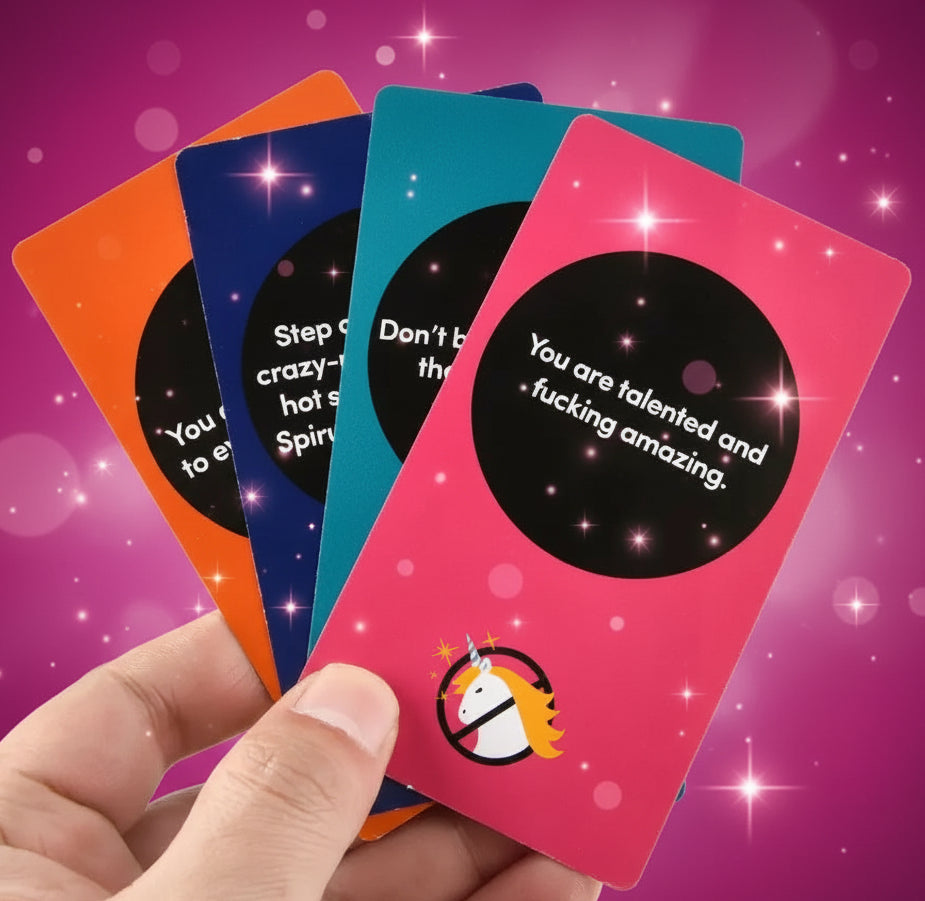 Hand holding colorful cards with motivational text and a unicorn illustration.