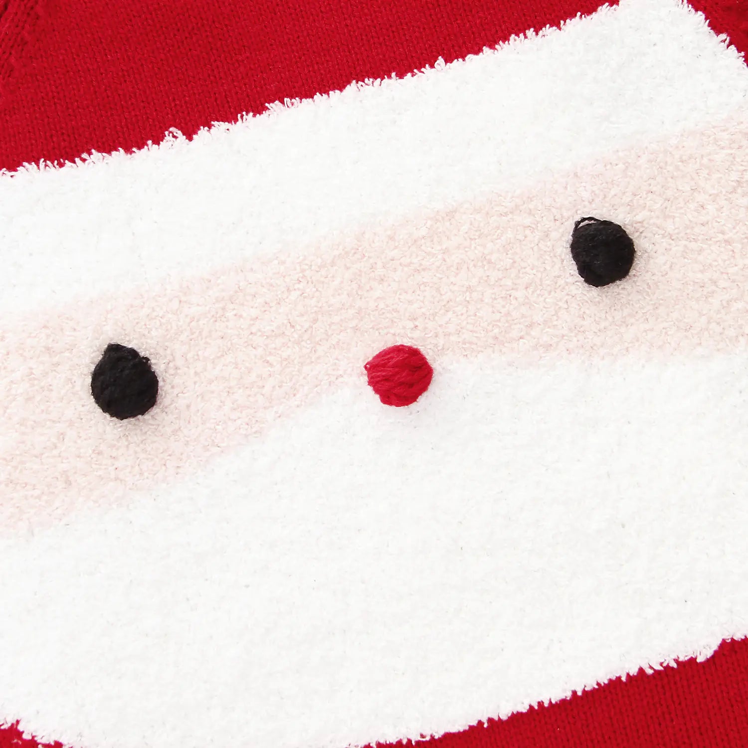 Close-up of a plush toy with a red nose and black eyes on a red background
