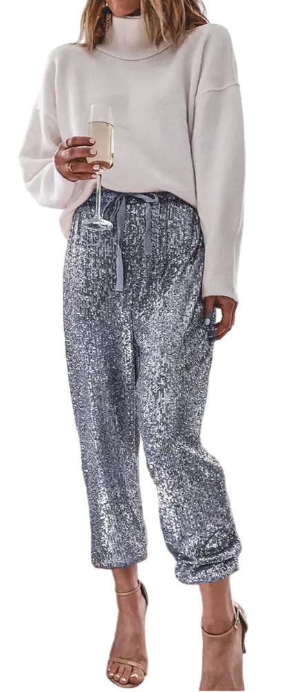 Woman in sequin pants holding a glass in a living room with a Christmas tree.