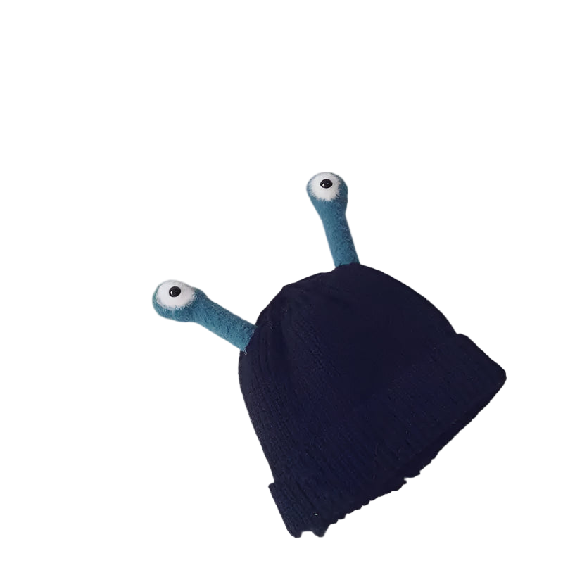 Black knit baby hat with blue alien ears and eyes on a light gray background